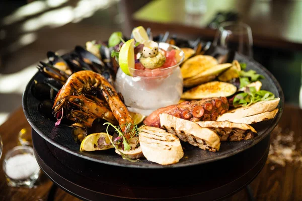 2-4 kişi için deniz ürünleri tabağı. Ahtapot, mavi midye, pişmiş yeşil midye, ızgara kaplan karidesi, ton balığı. Lezzetli deniz ürünleri modern gurme restoranında öğle yemeğinde servis edilir.