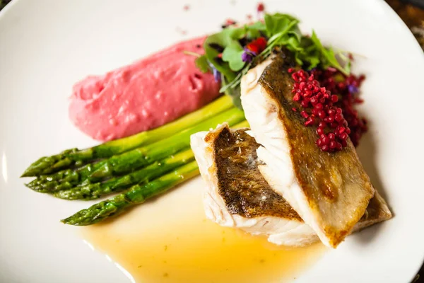 Pike-perch fillet. Asparagus, pearl couscous, white wine sauce, beet-flavored mashed potatoes. Delicious seafood fish closeup served on a table for lunch in modern cuisine gourmet restaurant — Stock Photo, Image