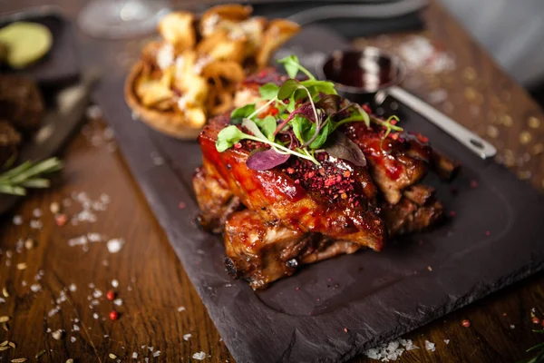 Schweinerippchen bei niedriger Temperatur gekocht. Schwarze Johannisbeersoße, Pastinakenchips mit Parmesan. Köstliche gesunde Fleischgerichte in Nahaufnahme, serviert auf einem Tisch zum Mittagessen im Gourmetrestaurant der modernen Küche — Stockfoto