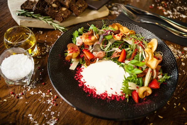 Salada de presunto crudo. Stracciatella e queijo Grana Padano, tomate seco, pepino fresco. Delicioso saudável misto greens comida closeup servido em uma mesa para o almoço na cozinha moderna restaurante gourmet. — Fotografia de Stock