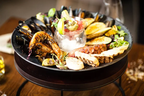 Plateau de fruits de mer pour 2-4 personnes. Poulpe, moules bleues, moules vertes cuites, crevettes tigrées grillées, tartare de thon. Délicieux gros plan de fruits de mer servi sur une table pour le déjeuner dans un restaurant gastronomique moderne — Photo