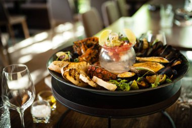 2-4 kişi için deniz ürünleri tabağı. Ahtapot, mavi midye, pişmiş yeşil midye, ızgara kaplan karidesi, ton balığı. Lezzetli deniz ürünleri modern gurme restoranında öğle yemeğinde servis edilir..