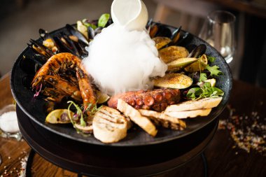 2-4 kişi için deniz ürünleri tabağı. Ahtapot, mavi midye, pişmiş yeşil midye, ızgara kaplan karidesi, ton balığı. Lezzetli deniz ürünleri modern gurme restoranında öğle yemeğinde servis edilir..