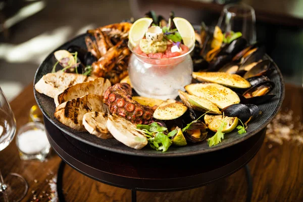 2-4 kişi için deniz ürünleri tabağı. Ahtapot, mavi midye, pişmiş yeşil midye, ızgara kaplan karidesi, ton balığı. Lezzetli deniz ürünleri modern gurme restoranında öğle yemeğinde servis edilir..