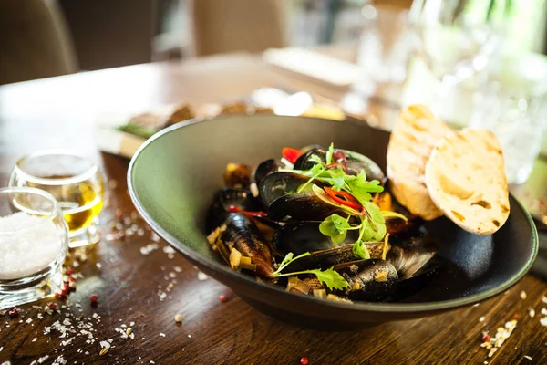 Siyah kasede beyaz şarap soslu mavi midye. Modern mutfak gurme restoranında öğle yemeği için sunulan lezzetli, sağlıklı deniz ürünleri..