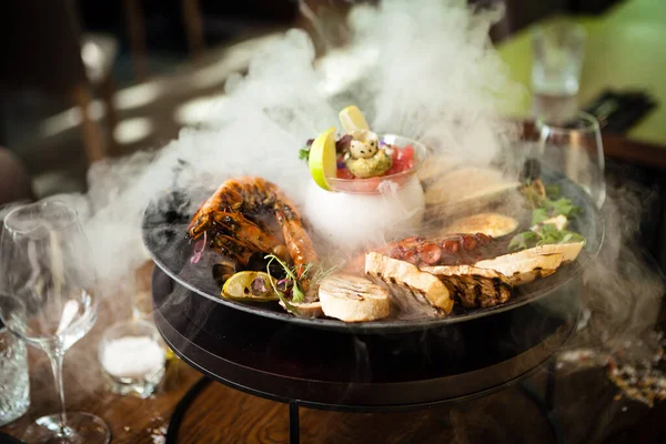 2-4 kişi için deniz ürünleri tabağı. Ahtapot, mavi midye, pişmiş yeşil midye, ızgara kaplan karidesi, ton balığı. Lezzetli deniz ürünleri modern gurme restoranında öğle yemeğinde servis edilir.