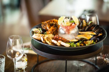 2-4 kişi için deniz ürünleri tabağı. Ahtapot, mavi midye, pişmiş yeşil midye, ızgara kaplan karidesi, ton balığı. Lezzetli deniz ürünleri modern gurme restoranında öğle yemeğinde servis edilir.