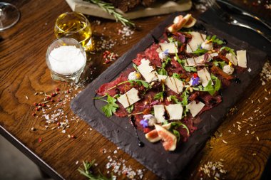 Biber, roka ve parmesanlı biftek carpaccio. Lezzetli sağlıklı İtalyan geleneksel antipasti aperatifleri yakın plan yemek servisi modern gurme mutfağında şarapla servis edilir.