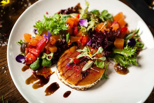 Insalata di formaggio di capra. Insalata di fragole e melone con peperoncino, salsa di mele e arancia, marmellata di fichi su piatto bianco. Delizioso primo piano di carne servita su un tavolo per il pranzo in cucina moderna ristorante gourmet — Foto Stock