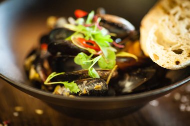 Siyah kasede beyaz şarap soslu mavi midye. Modern mutfak gurme restoranında öğle yemeği için sunulan lezzetli, sağlıklı deniz ürünleri..