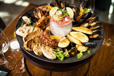 2-4 kişi için deniz ürünleri tabağı. Ahtapot, mavi midye, pişmiş yeşil midye, ızgara kaplan karidesi, ton balığı. Lezzetli deniz ürünleri modern gurme restoranında öğle yemeğinde servis edilir..