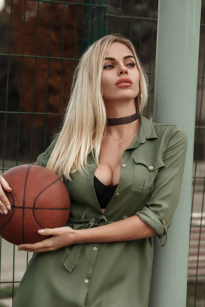 Boynuna gerdanlık ile büyük göğüsler ile yeşil giysili güzel sarışın ile Basketbol basketbol sahası üzerinde duruyor