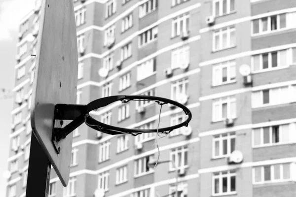 Basketball ring isolated with metal mesh at house background. Urban view. Monochrome photo. Black and white image. Sport concept