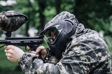 Paintball oyuncusunun Koruyucu Maske ve Kamuflaj Piksellerinde Paintball işaretiyle tam teçhizatlı portresi