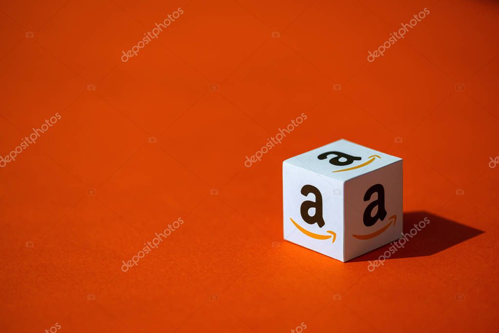 Kyiv, Ukraine - September 10, 2019: A shot of paper cube with the printed logotype of the Amazon company, that placed on an orange background.