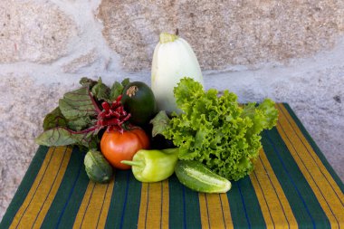 Salatalık, domates ve kabak dahil olmak üzere çeşitli sebzeler bir masada sergilenir. Sebzelerin düzenlenmesi renkli ve sağlıklı bir manzara yaratır.