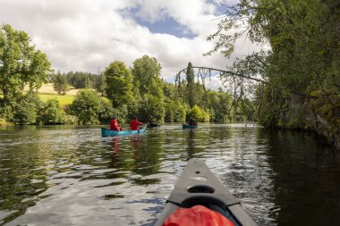 İskoçya, Birleşik Krallık, 4 Ağustos 2025: Bir grup insan bir nehirde kano çırpıyor. Su sakin ve gökyüzü bulutlu.