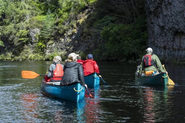 İskoçya, Birleşik Krallık, 4 Ağustos 2025: Üç kişi bir nehirde kanolarda kürek çekiyor ve manzaranın tadını çıkarıyorlar. Manzara huzurlu ve rahatlatıcı..
