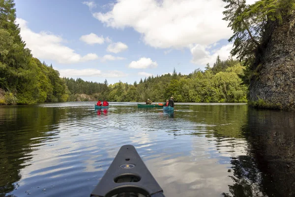 İskoçya, Birleşik Krallık, 4 Ağustos 2025: Bir grup insan bir gölde kürek çekiyor. Su sakin ve gökyüzü berrak.