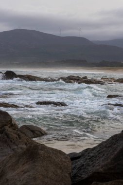 Okyanus dalgalı ve dalgalar kayalara çarpıyor. Gökyüzü bulutlu ve arka plandaki dağlar sisle örtülü. Sahne, okyanus gibi güç ve öngörülemezlikten gelir.