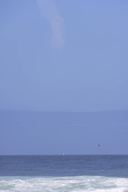 Suda teknesi olan mavi bir gökyüzü. Gökyüzü açık ve su sakin.