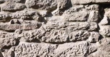 Kaba bir dokusu olan taştan yapılmış bir duvar. Duvar gri ve birkaç çatlağı var.