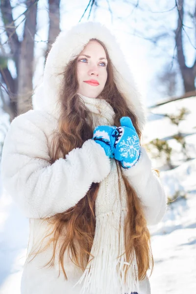 雪と木の背景に長い髪と青い目の白い毛皮のコートの女の子 — ストック写真