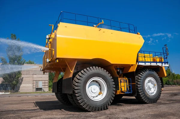 heavy yellow irrigating machine watering ground at sunny cloudless day