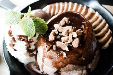 Lezzetli krep muzlu çikolata ve vanilyalı dondurma. Siyah demir tepside, alet altlığının üstünde..