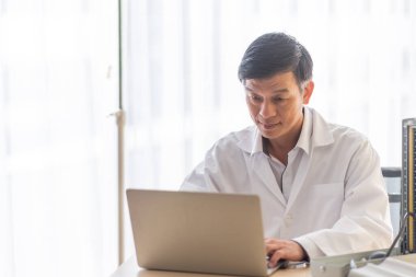 Masada gülümseyen doktor dizüstü bilgisayar kullanıyor 