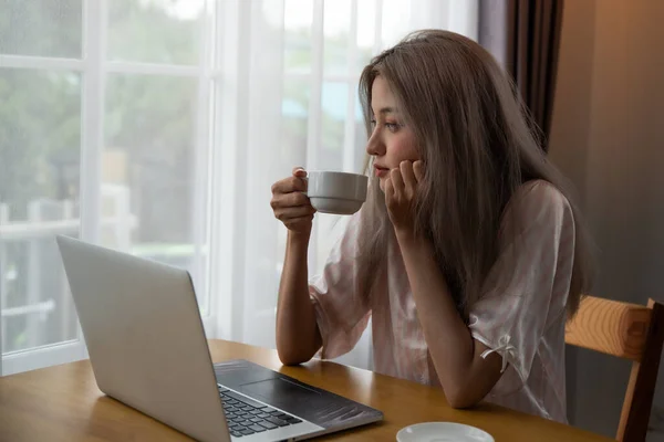 Lazy woman drinking morning coffee at home.