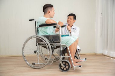 Doktor ve hasta hastanede tekerlekli sandalyede otururken tartışıyorlar. 