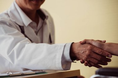 Hastanedeki kadın hastayla el sıkışan erkek doktorun kesilmiş resmi. 
