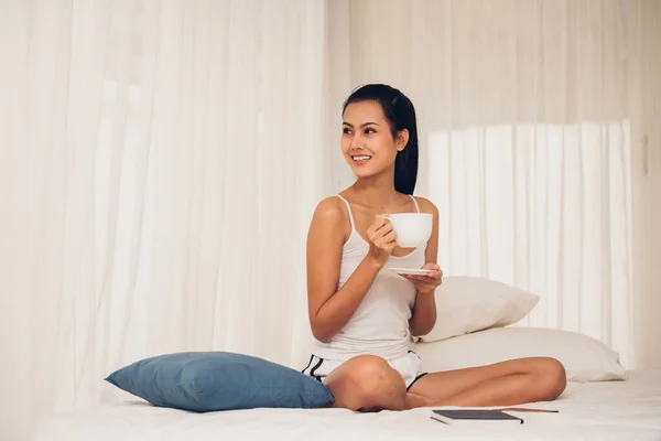 Retrato Sorrindo Jovem Mulher Segurando Xícara Café Enquanto Sentado Cama — Fotografia de Stock