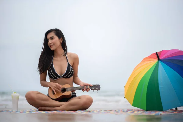 Frau Spielt Ukulele Während Sie Strand Gegen Den Himmel Sitzt — Stockfoto