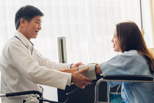 Doktor, klinikteki hastanın kan basıncını ölçüyor. 