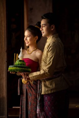 Thai couple in traditional dress costume making and decorating Krathong. Loy Krathong Festival. clipart