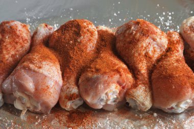 Pişirmeden önce tuz ve kırmızı biber serpiştirilmiş çiğ tavuk budu..