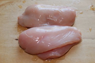 Taze tavuk filetosu ahşap yüzeyde kapanıyor..