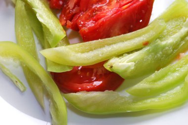 Dilimlenmiş domates ve tatlı biber beyaz yüzeyde kapanıyor..