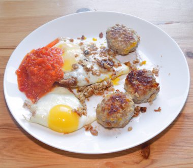 Kızarmış yumurta ve beyaz tabak üzerinde et pirzolası.