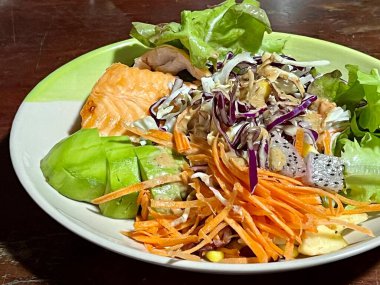 Somonlu salata ve ahşap bir masada taze sebzeler.