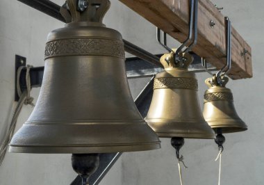 Three bells hanging on the crossbar in the bell tower. clipart
