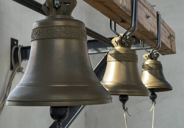 Three bells hanging on the crossbar in the bell tower.