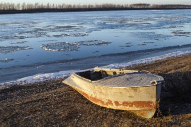 Dondurucu bir nehir ve sahilde yalnız bir tekne.