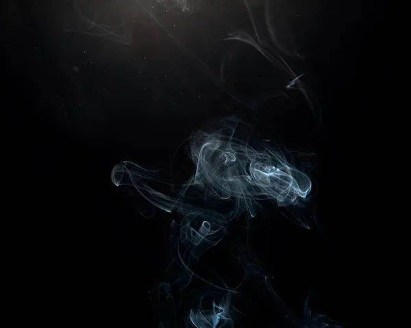 Wispy smoke and fine floating particles over a dark background with a slight lens flare.