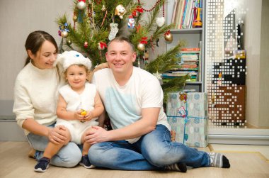 Mutlu aile Noel ağacının yanında oturuyor.