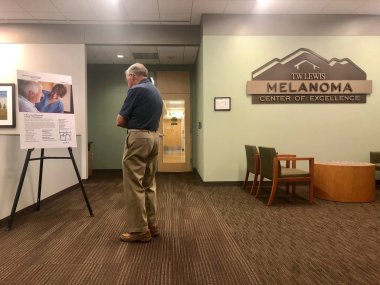 Bir poster üzerinde bazı malzeme okurken doktoru ziyaret etmek için MD Anderson tesisin Melanoma merkezinde bekleyen hasta. MD Anderson, Gilbert, Amerika Birleşik Devletleri 'nin Arizona kesiminde yer almaktadır.