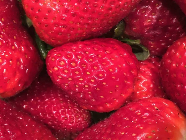 Closeup of Strawberries sitting together in box waiting to eaten. The garden strawberry is a widely grown hybrid species of the genus Fragaria, collectively known as the strawberries. It is cultivated worldwide for its fruit.