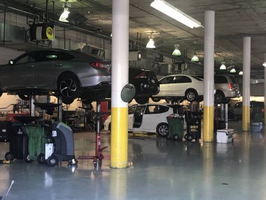 Onarım için kaldırma platformu üzerinde bir araba tamir dükkanında Araçlar. Arka planda özel tamir ekipmanları ile oto tamir servisi dükkanı için garajda Arabalar.